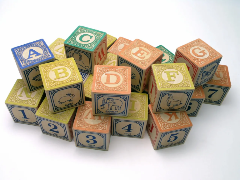 A set of colorful wooden alphabet blocks is arranged on a light wooden surface. Each block features bold, uppercase letters in vibrant colors such as red, blue, green, and yellow. The blocks are neatly stacked and scattered, inviting children to engage in letter recognition, word building, and early literacy activities. These Montessori-inspired alphabet blocks promote language development in early childhood by helping toddlers and preschoolers learn the alphabet, letter sounds, and simple word formation. The smooth, natural wood texture of the blocks offers a tactile experience, making them ideal for hands-on learning and language growth through play.